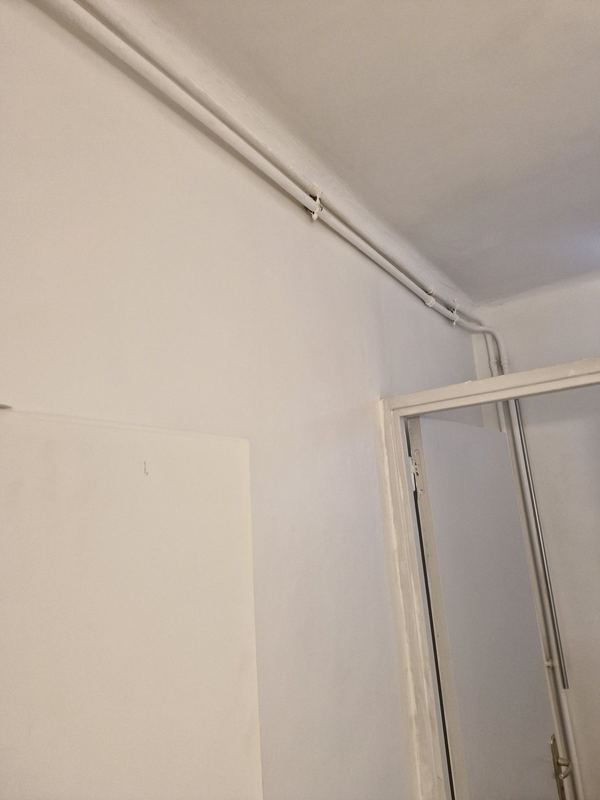 Après : mur et plafond de salle de bain repeints en blanc, tuyaux et encadrement de porte peints