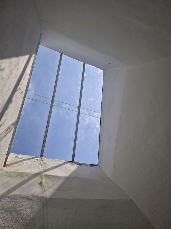 Verrière de toit vue de l'intérieur après remplacement des vitres : verre neuf et ciel bleu