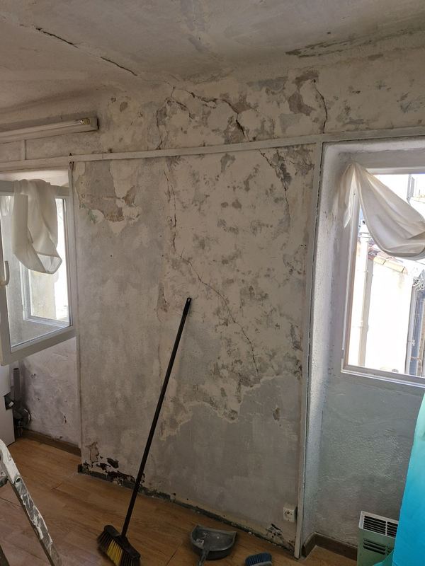 Avant : mur fissuré et écaillé entre deux fenêtres