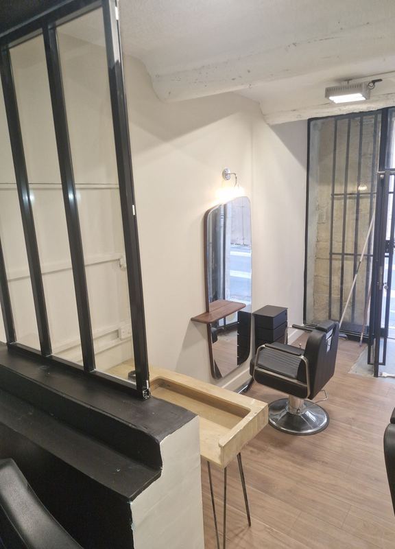 Salon de coiffure terminé : fauteuil, miroir, verrière et sol effet bois